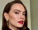 Elegancka kobieta z wyraźnym przedziałkiem po boku, w błyszczących kolczykach i z intensywną czerwoną szminką.