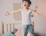 Bambino iperattivo 4 anni cosa fare? Un bimbo salta sul letto, pieno di energia.