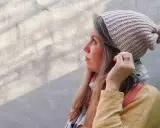 Mujer con gorro tejido a crochet, con pompón rosa. Disfruta del proceso de tejer gorros crochet.