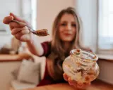 Frau mit Löffel und leerem Glas Apfelmus. Ein kleiner Fehler beim Einkochen, aber lecker!