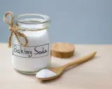 Słoik z napisem "Baking Soda" i drewniana łyżka z proszkiem. To naturalny sposób na usuwanie plam.
