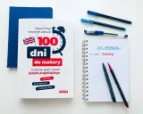 Książka "100 dni do matury" i notatnik z długopisami sugerują, jak zdać maturę z angielskiego.