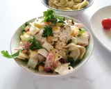 Pyszna sałatka z tortellini, jajka, kukurydzy i pomidorów, udekorowana natką pietruszki. Idealna na letnie dni.