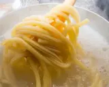 Gorący garnek z bulgoczącą wodą, z którego wyciągane są idealne, sprężyste nitki makaronu al dente.