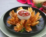 Eine knusprige, blühende Zwiebel, die wie eine Blume aussieht, mit einem Dip in der Mitte.