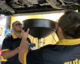 Mecánicos observan el aceite de la caja de cambios drenando en un recipiente. Es el momento de saber cuándo cambiar aceite caja de cambios.