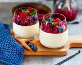 Zwei Gläser mit cremigem Panna Cotta, garniert mit Beeren und Minze. Ein köstliches Rezept für original italienische Panna Cotta.