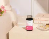 Flacon d'acide folique Novoma, un bienfait pour la grossesse et l'énergie, à côté d'un verre d'eau et de fleurs roses.