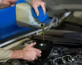Mecánico vertiendo aceite nuevo en el motor para el mantenimiento del coche.