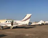 Mehrere weiße Cessna zweimotorig Flugzeuge stehen auf dem Flugplatz. Eines hat die Tür geöffnet.