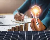 Opłata mocowa a fotowoltaika: rosnące stosy monet z wiatrakami i żarówką symbolizują inwestycje w zieloną energię.