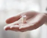 Eine Hand hält einen Stapel bunter Pillen. Vielleicht L-Arginin vor dem Schlafen für einen erholsamen Schlaf.
