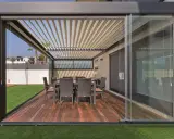 Porches cerrados con encanto, con mesa y sillas de mimbre sobre tarima de madera y césped artificial.