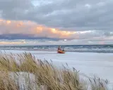 Ein kleines Boot liegt am verschneiten Strand der Ostsee, im Hintergrund die Seebrücke von Ahlbeck.