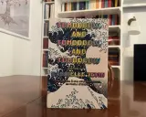 Copertina del libro "Tomorrow, and tomorrow, and tomorrow" di Gabrielle Zevin, con onde stilizzate e testo ripetuto.