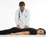 Terapeuta wykonuje delikatne ruchy na plecach pacjentki, co ilustruje, na czym polega terapia Bowen'a.