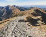 Kamienista ścieżka prowadzi przez trawiaste zbocza, ukazując najpiękniejsze doliny Zakopane. W oddali majaczą góry.