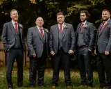 Five men in matching grey suits with red ties and pocket squares. The price of tuxedos can vary, but these look like a good investment for a wedding party.