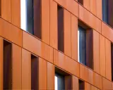 Fachada de edificio revestida con paneles de acero corten, creando un efecto oxidado y moderno.