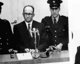 Adolf Eichmann w szklanej kabinie, otoczony strażnikami. Jego proces był transmitowany na cały świat, budząc grozę i pytania o losy dzieci.