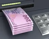 Stos banknotów po 200 lir tureckich wychodzi z bankomatu. To pokazuje, jakie pieniądze w Turcji można wypłacić.