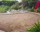 A cleared, sandy patch of yard, ready for new planting. This area, once grass, is now prepped for a garden, showing how to kill grass for a fresh start.