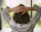 En person med händerna bakom huvudet, klädd i en randig tröja, tar en stund att hitta tillbaka efter paus.