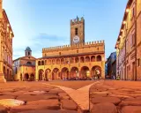 Piazza del Popolo a Ripatransone, un gioiello per un itinerario Marche 5 giorni. Edifici storici illuminati, torre con orologio e ciottoli antichi.