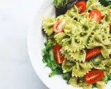 Pyszna sałatka z makaronem farfalle w sosie pesto, z pomidorkami koktajlowymi i świeżą sałatą.