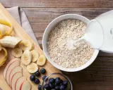 Haferflocken mit Milch, geschnittener Banane, Äpfeln und Blaubeeren. Eine gesunde Mahlzeit, die hilft, Cholesterin zu senken.