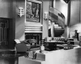 Elegantes Wohnzimmer im **art deco stil** mit geschwungener Treppe, Kamin und stilvollen Möbeln.