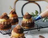 Finition d'une religieuse au chocolat avec une touche de crème. Ces pâtisseries sont prêtes à être dégustées.