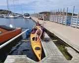 Förberedelser för kajakpaddling i Lysekil. En gul kajak ligger i vattnet vid en brygga, redo för äventyr.