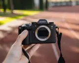 Dłoń trzyma aparat Sony Alpha 9 z obiektywem. Jego zaawansowany **global shutter** pozwala na uchwycenie dynamicznych scen bez zniekształceń.