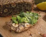 Ein Stück herzhaftes Flohsamenschalen Brot mit Nüssen, belegt mit Avocado und Kresse. Ein gesunder Genuss!