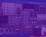 Un homme au chapeau parle dans un micro, entouré d'écrans affichant des logiciels pour faire des prods musicales.
