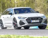 Białe Audi RS6 Avant na torze, kierowca wpatrzony przed siebie.