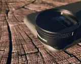 Un lente de cámara con la marca "NOMARC" descansa sobre un teléfono, listo para capturar imágenes con sus ópticas anamórficas.