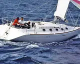 Voilier blanc naviguant sur une mer agitée. Trois personnes à bord. Le numéro 3517 est visible sur la coque.