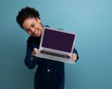 Uśmiechnięta kobieta prezentuje laptopa, gotowa do sprzedaży. Dowiedz się, jak przygotować laptop do sprzedaży, by uzyskać najlepszą cenę.