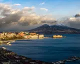 Vista panoramica di Napoli con il Vesuvio innevato sullo sfondo, il Castel dell'Ovo e il lungomare.