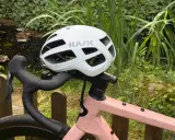 Biały kask rowerowy KASK na kierownicy różowego roweru. Przygotowany do jazdy, zgodnie z przepisami ruchu drogowego dla rowerzystów.