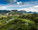 Malownicze **Pieniny** w okolicach **Szczawnicy** z meandrującym Dunajcem, zielonymi łąkami i skalistymi szczytami pod błękitnym niebem.
