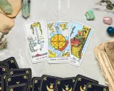 Karta życia tarot: As Mieczy, Koło Fortuny i Król Buław. Tajemnicze kryształy i stare księgi dopełniają mistyczną atmosferę.