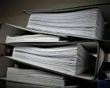 Stosy dokumentów w segregatorach. Może to być materiał do analizy, ale też dowód na to, że popełniono błąd i teraz potrzebny jest czynny żal.