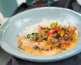 En krämig kyckling- och risrätt med paprika och svamp, garnerad med färska örter. En härlig måltid som ser utsökt ut.