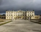 Pałac Branickich w Białymstoku, majestatyczna budowla z ogrodem, pod burzowym niebem.