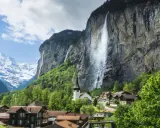 Lauterbrunnen Wasserfall stürzt von einer Felswand, umgeben von einem Dorf und schneebedeckten Bergen.