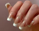 Dłoń z paznokciami w stylu odwrócony french. Klasyczny manicure z białym wykończeniem i naturalnym kolorem płytki.