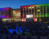 Wieczorny seans pod gołym niebem przed Galerią Krakowską. Tłum widzów w leżakach ogląda film na wielkim ekranie.